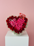 Heart-shaped arrangement of red and pink roses with a 'Happy Valentine's Day' card on a pink background